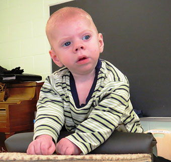 A young boy with disabilities, with the help of his prone stander, picks his head up to discover the world around him
