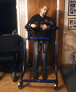 Pacer XL Adult Gait Trainer Tall Walker Casey Breyette stands in his blue Pacer XL adult gait trainer helping him ambulate around his home for a quicker recovery from his traumatic brain injury