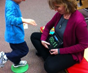 Therapist Connie Johnson uses an iPad add to help a young boy with disabilities work on balancing.