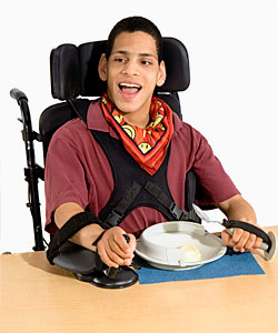 A young man in a Rifton chair uses arm stabilizers to assist him with improving his functional ability so he can participate in mealtime