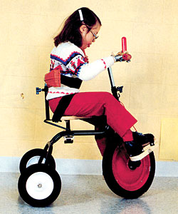 A young girl rides Rifton Tricycle as she tests the various features of the product