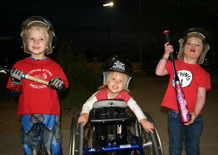 Madi using her special needs equipment to play t-ball smiles alongside her brother and friend.
