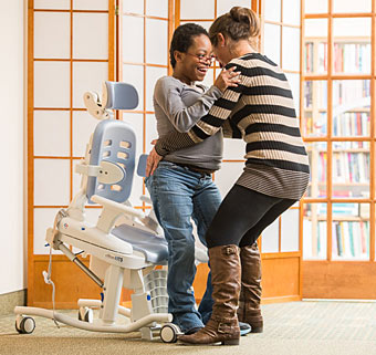 A therapist uses special needs toileting equipment to provide hygiene care for a patient.
