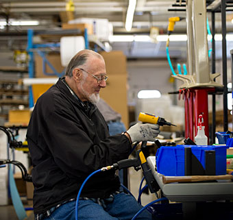 A worker changes the setting on a drill assembling components for adaptive equipment at the manufacturing facility in Rifton