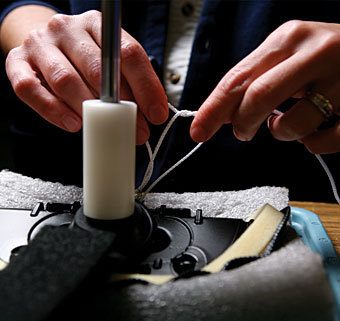 A woman tying a string on a crafted accessory piece covered with foam and fabric
