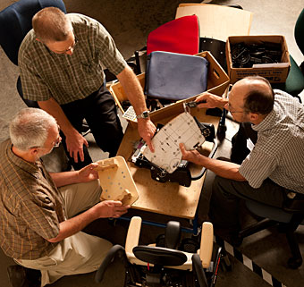 A group of designers sitting around a table at the Rifton manufacturing facility in the USA work on updates to the Activity chair