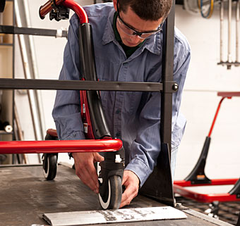 A worker assembling a red Rifton gait trainer at the USA manufacturing facility in Rifton