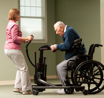 A therapist guides a home care patient in a sit-stand transfer