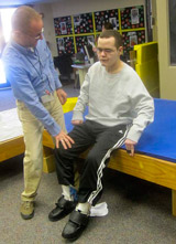 A TBI patient, with the help from his therapist works on properly positioning his head and trunk.