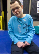 A TBI patient sits on a mat working on a variety of motor skills.