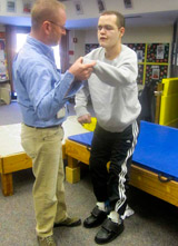 A TBI patient, with help from his therapist works on standing and stepping.