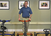 Webinar presenter demonstrating the large Rifton Pacer gait trainer