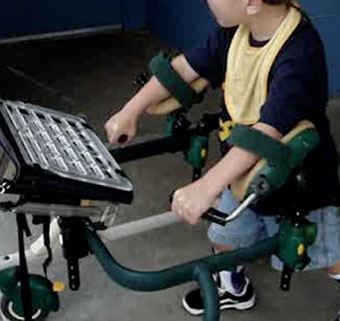 A young boy in a gait trainer using arm accessories to properly position the limbs downward in preparation for prompt reduction