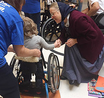 Customer service representatives from Rifton shake hands with children in a variety of special needs devices on a visit to Laremont School in Chicago