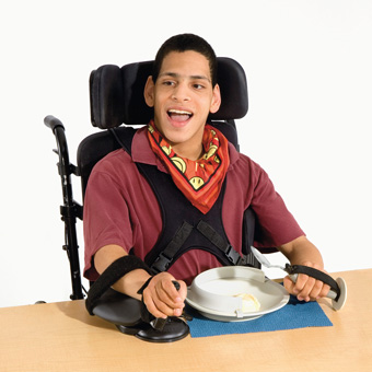 A young man eating icecream at a table.