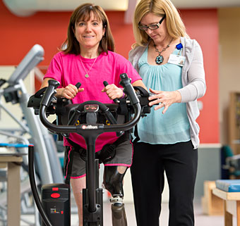 A therapist guides a rehab patient using a dynamic gait system to learn to walk again