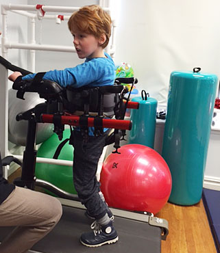 A young boy uses a Dynamic Pacer to to practice partial weight supported treadmill training 