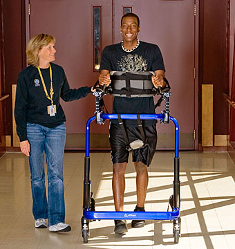 A young man works in rehabilitation on overground gait training in the Rifton Pacer gait trainer.