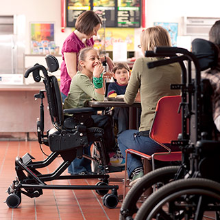 A young girl smiles as she sits in her activity chair in the cafeteria during her child-focused intervention curriculum.