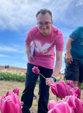 A young man picks a tulip and smiles.