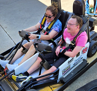 A young man and a young woman ride in a go-cart.