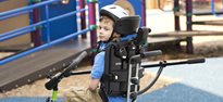 A young man using the Rifton adaptive tricycle's stationary stand for indoor trike practice